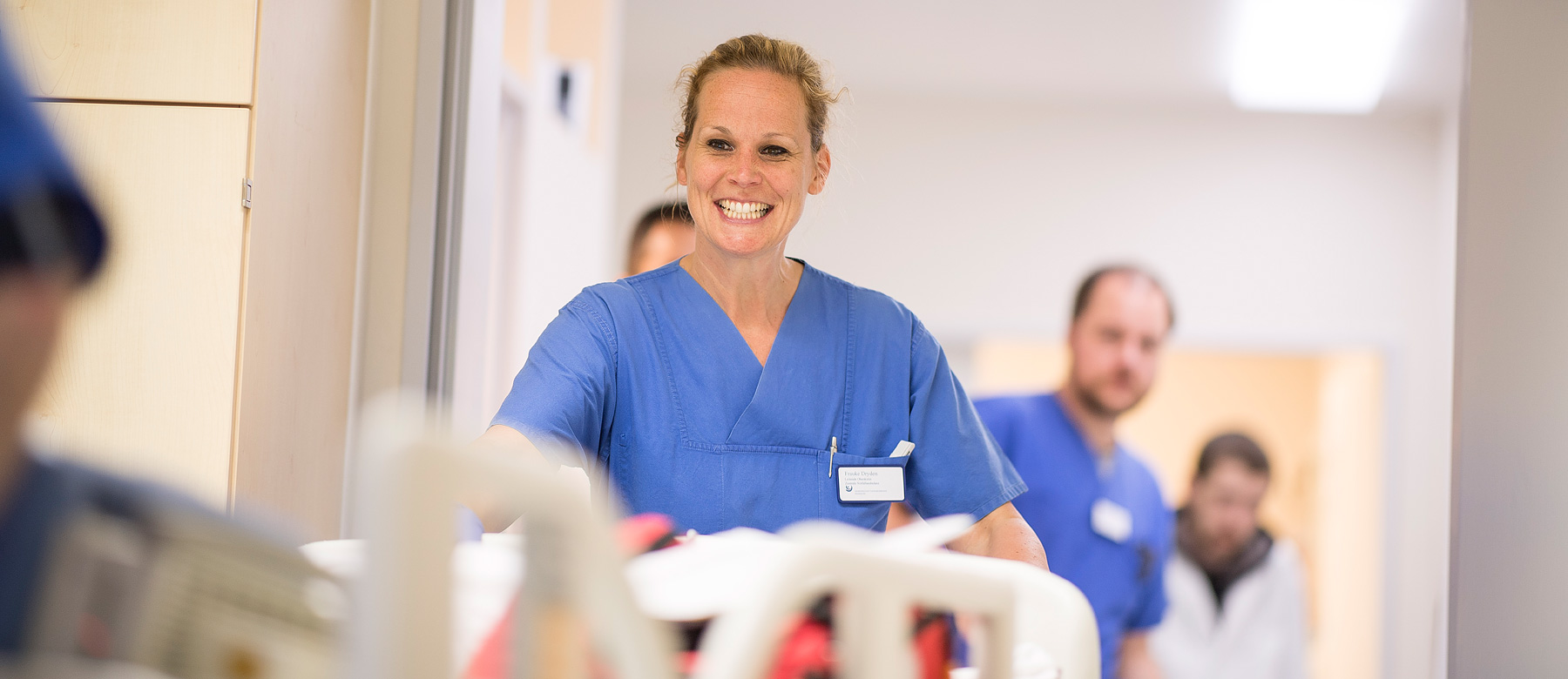 Frauke Dryden, Leitende Ärztin der Notaufnahme, lächelt einen Patienten im Patientenbett an.
