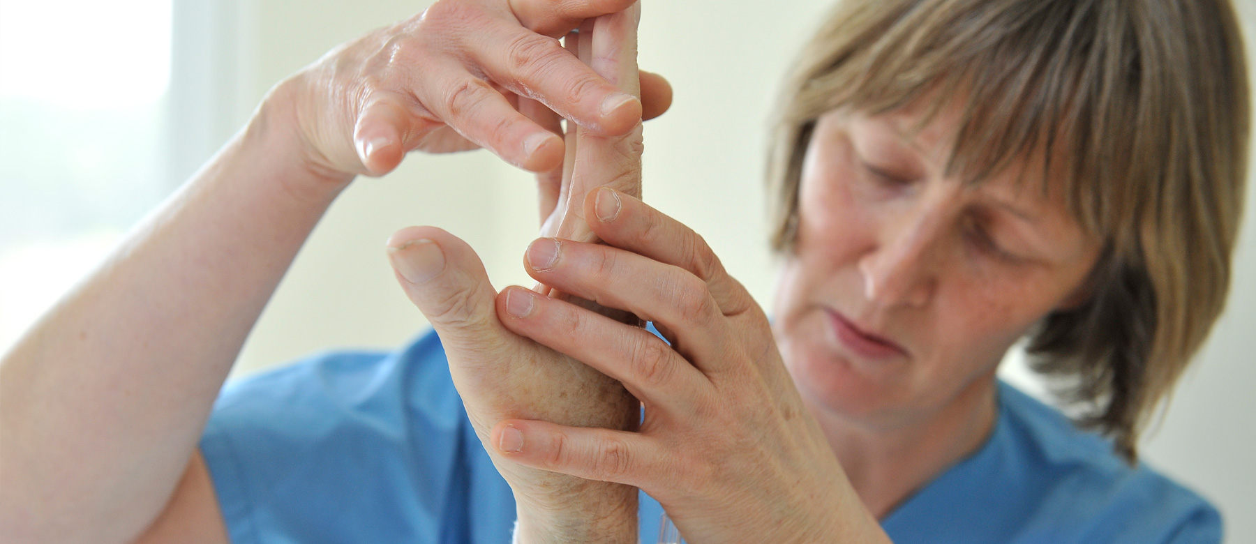 Physiotherapeutin behandelt die Hand eines Patienten.